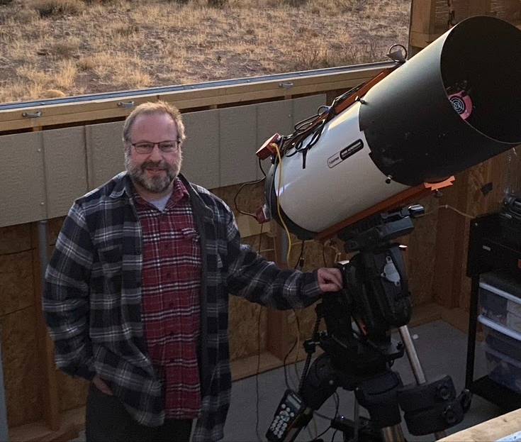 Seth McGowan stands next to a telescope