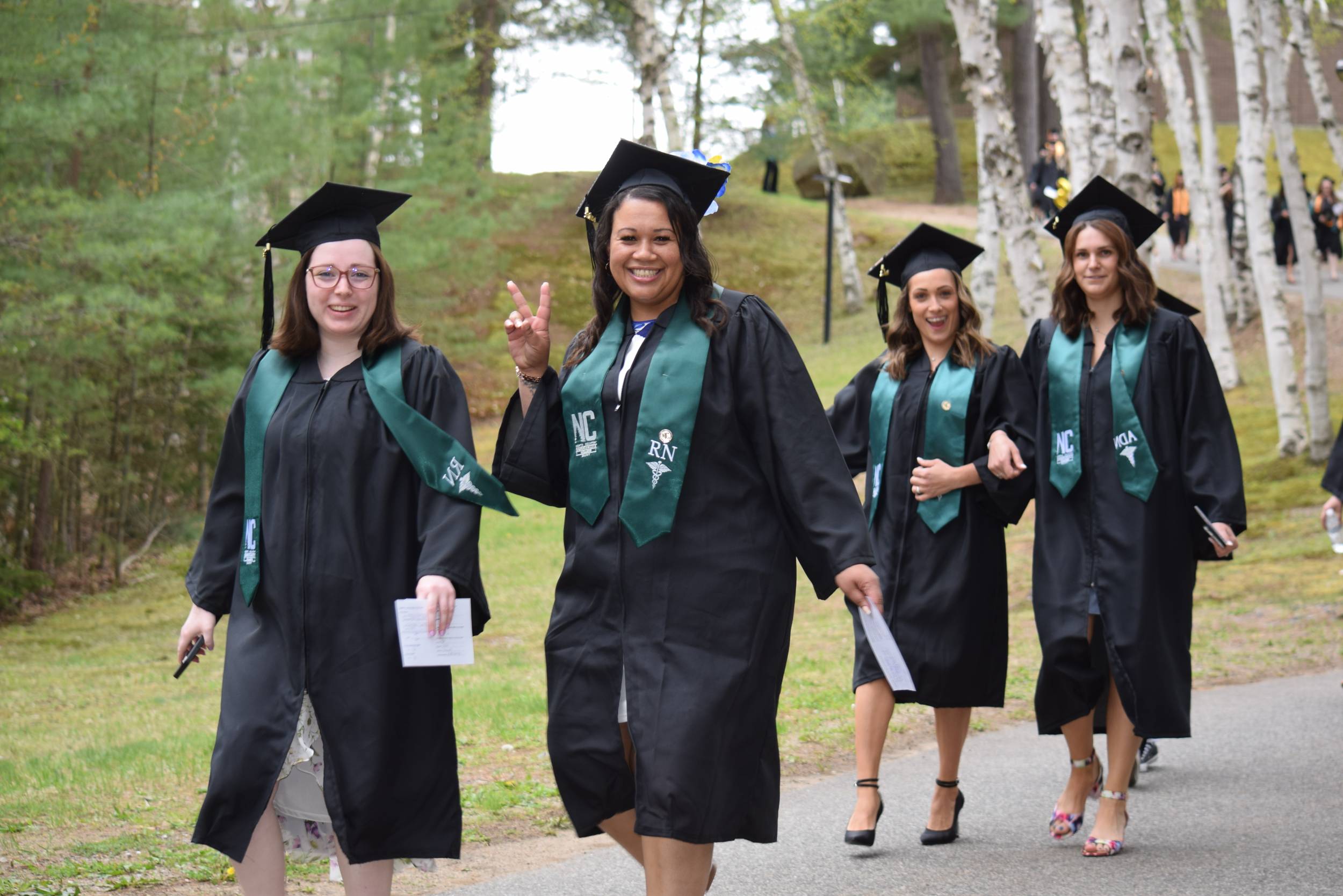 Students smile at the camera as they walk to commencement