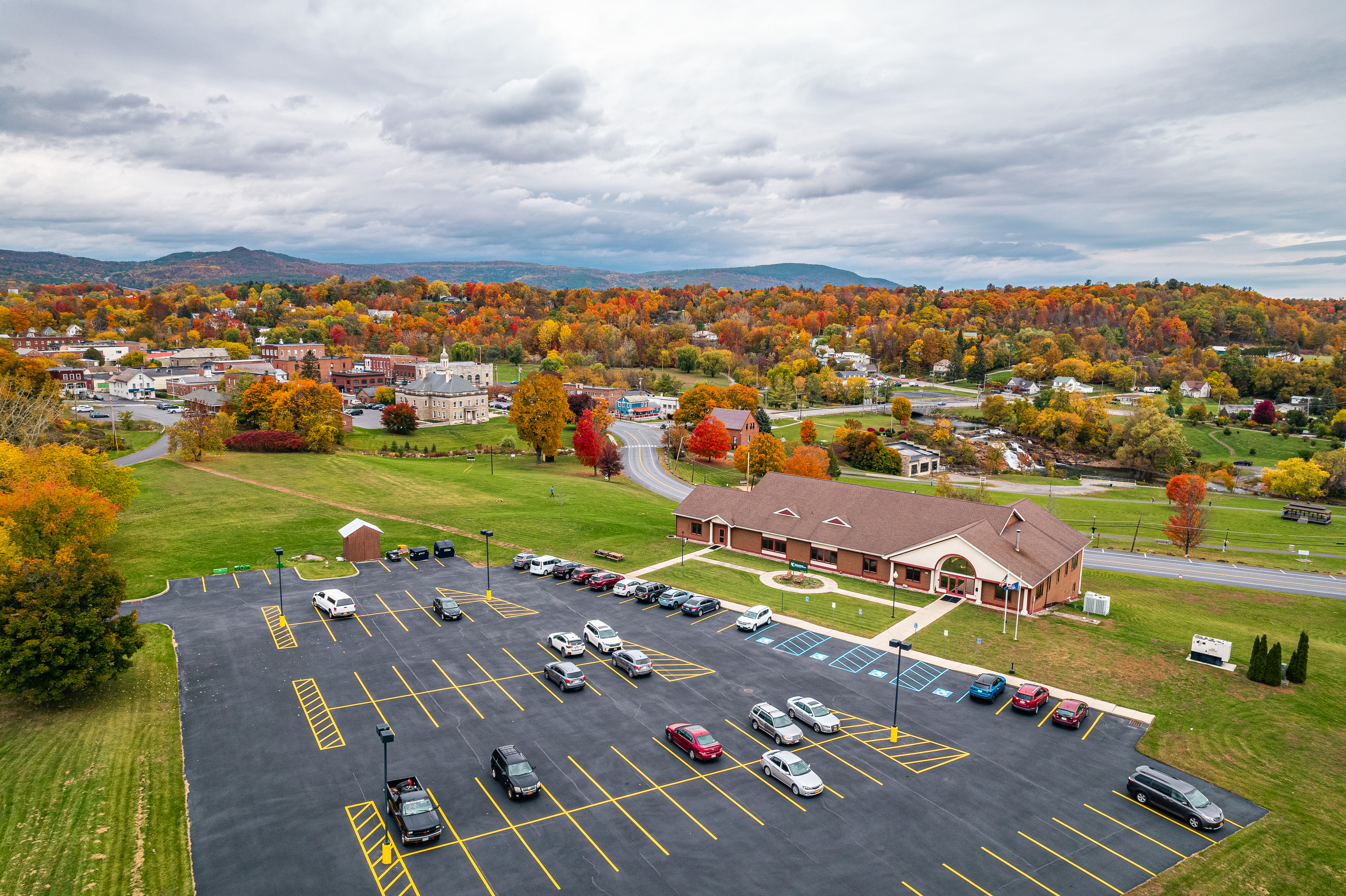 An aerial view of the college's Ticonderoga campus showing a parking lot in the foreground, the campus building, and the community and setting of Ticonderoga