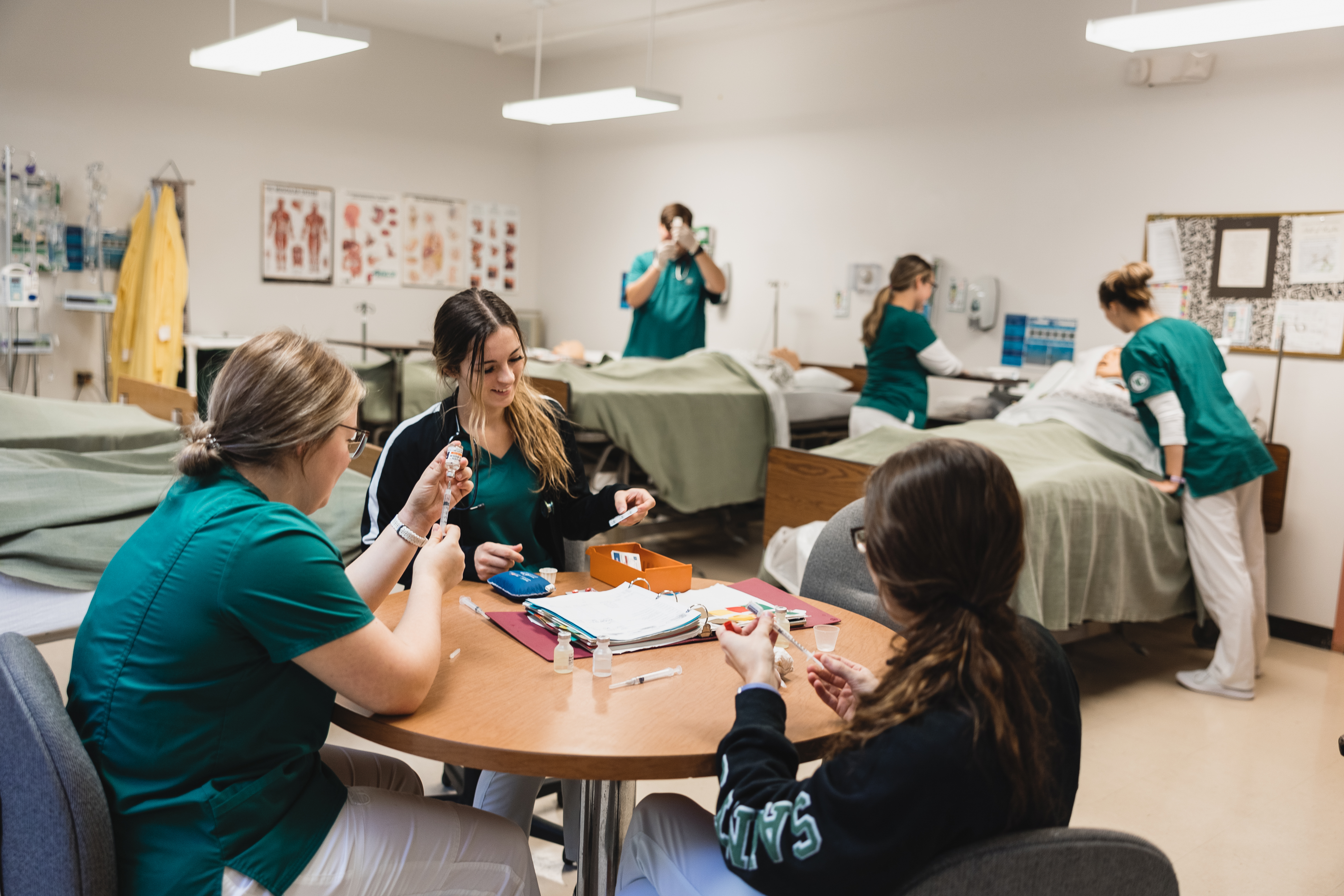 Students in the nursing program work in groups at tables