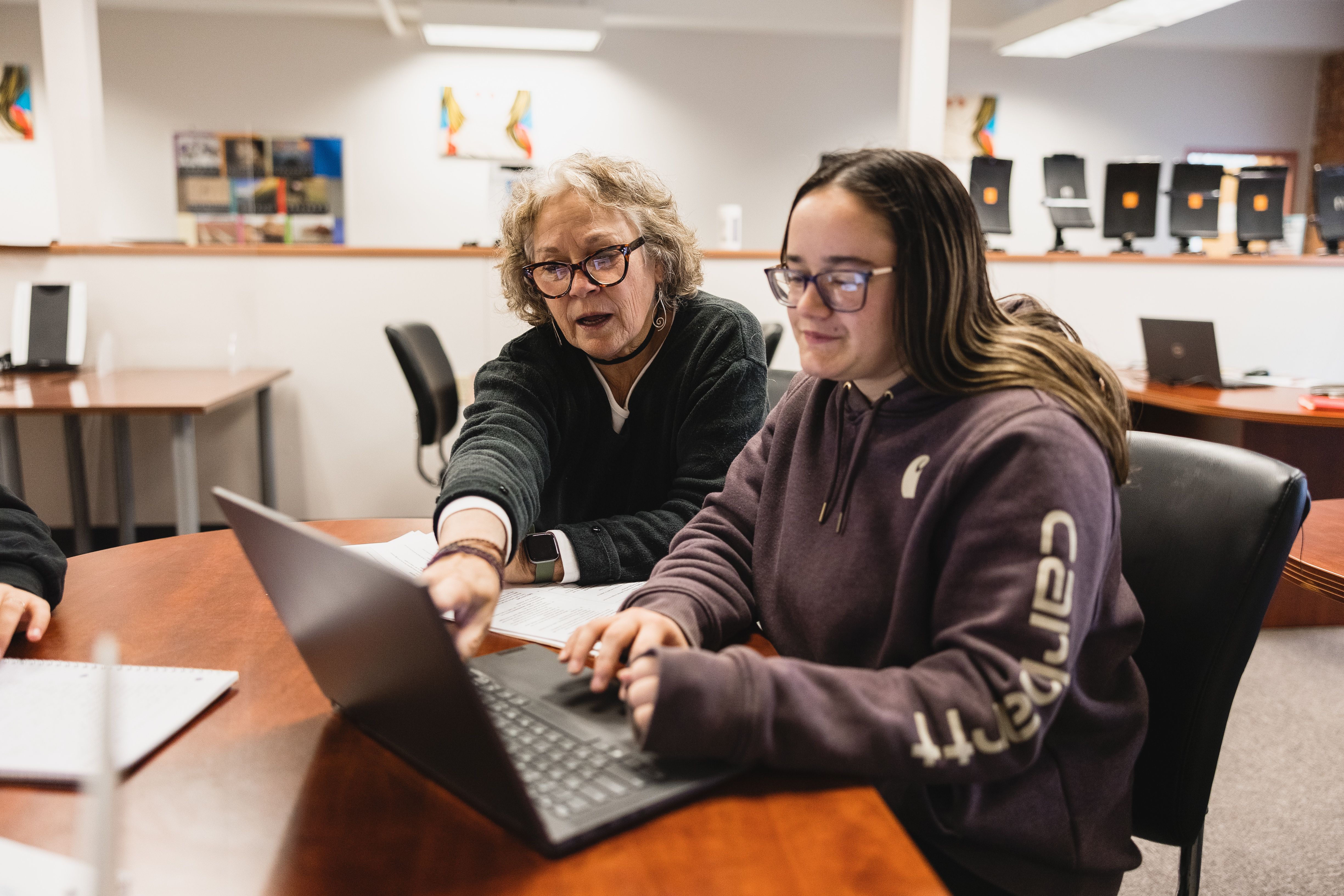 An instructor works with a student at a desk 