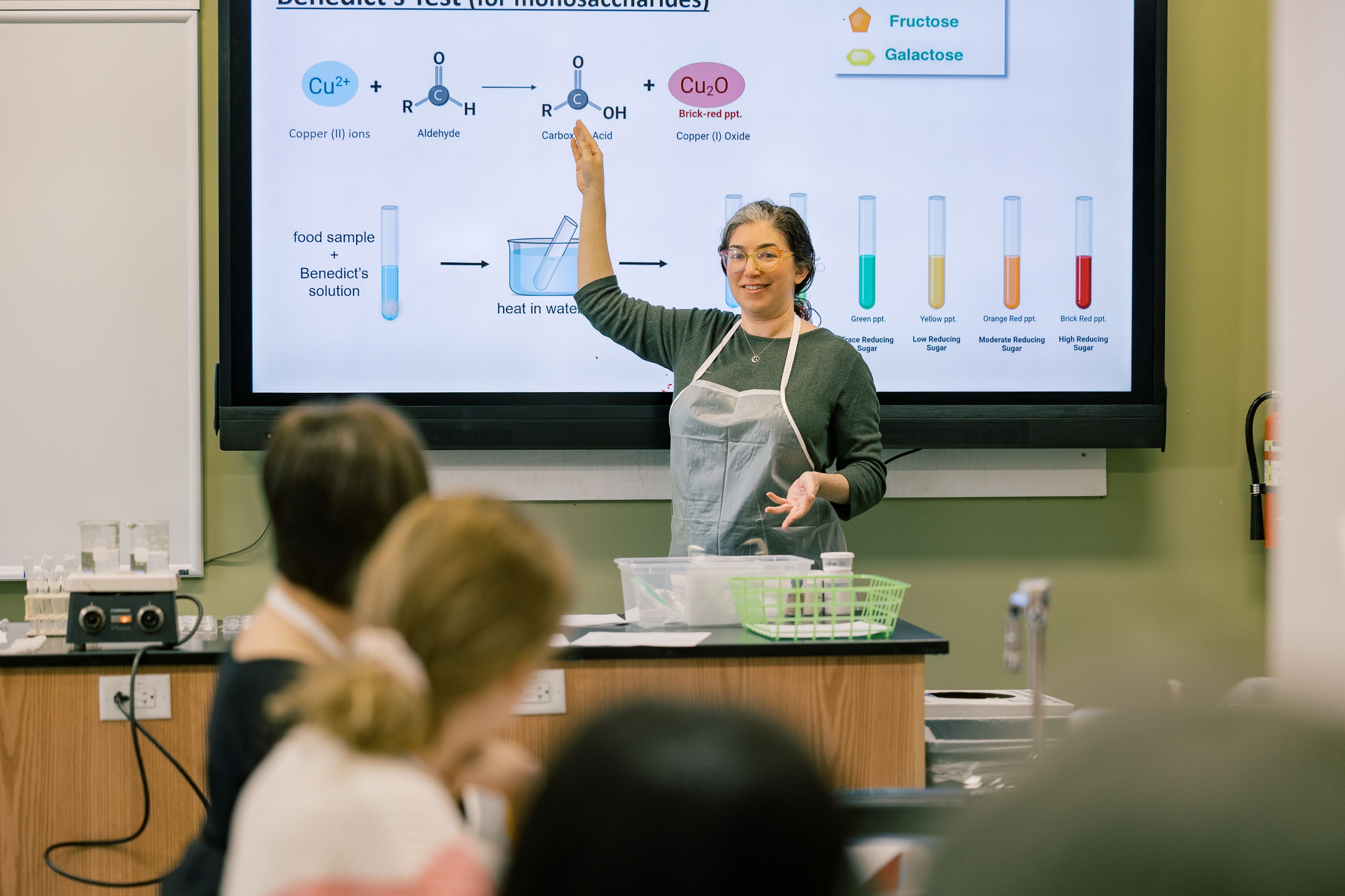 An instructor stands in front of a group of college students teaching science