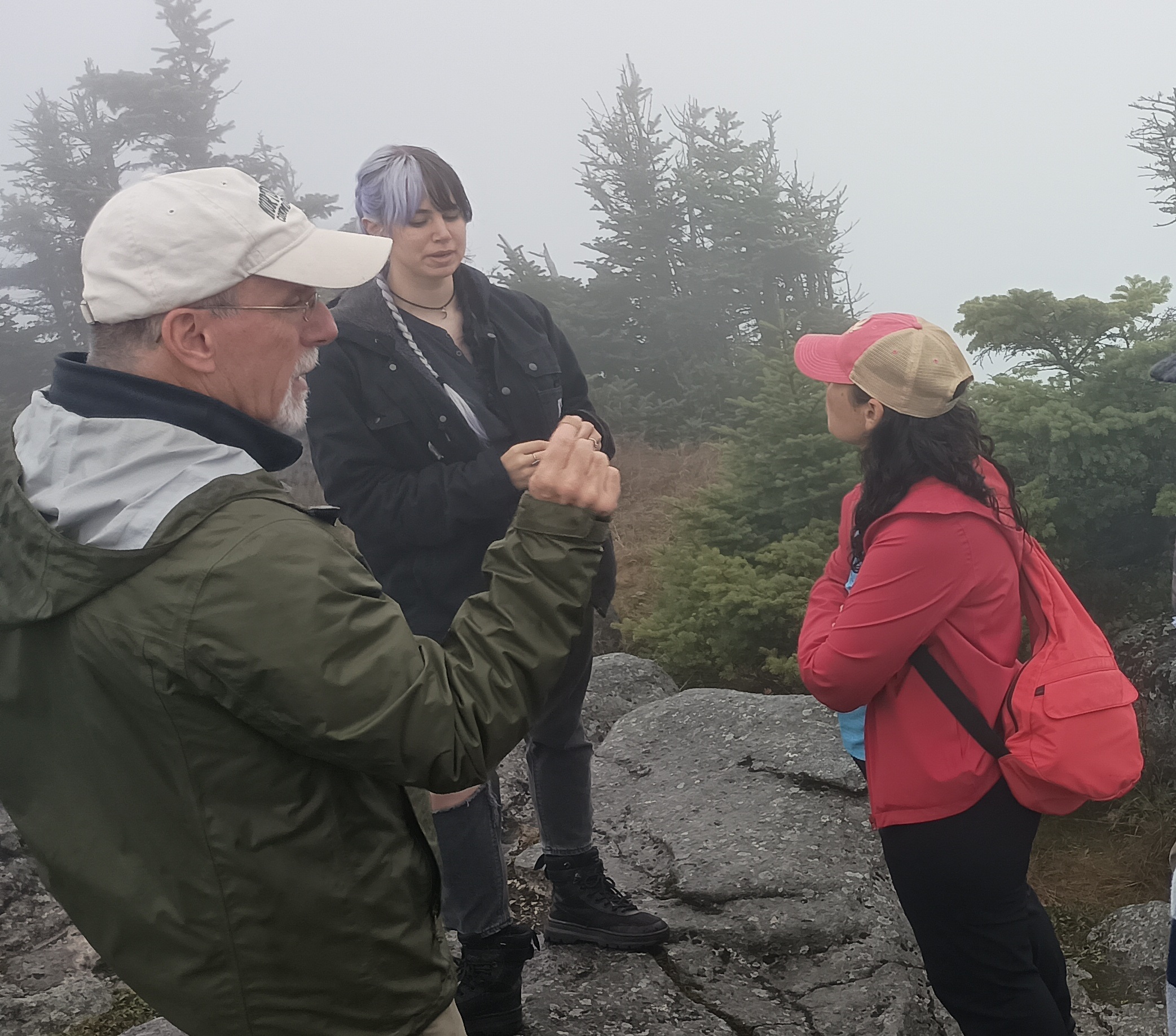 An instructor speaks to a group of college students on a mountain summit