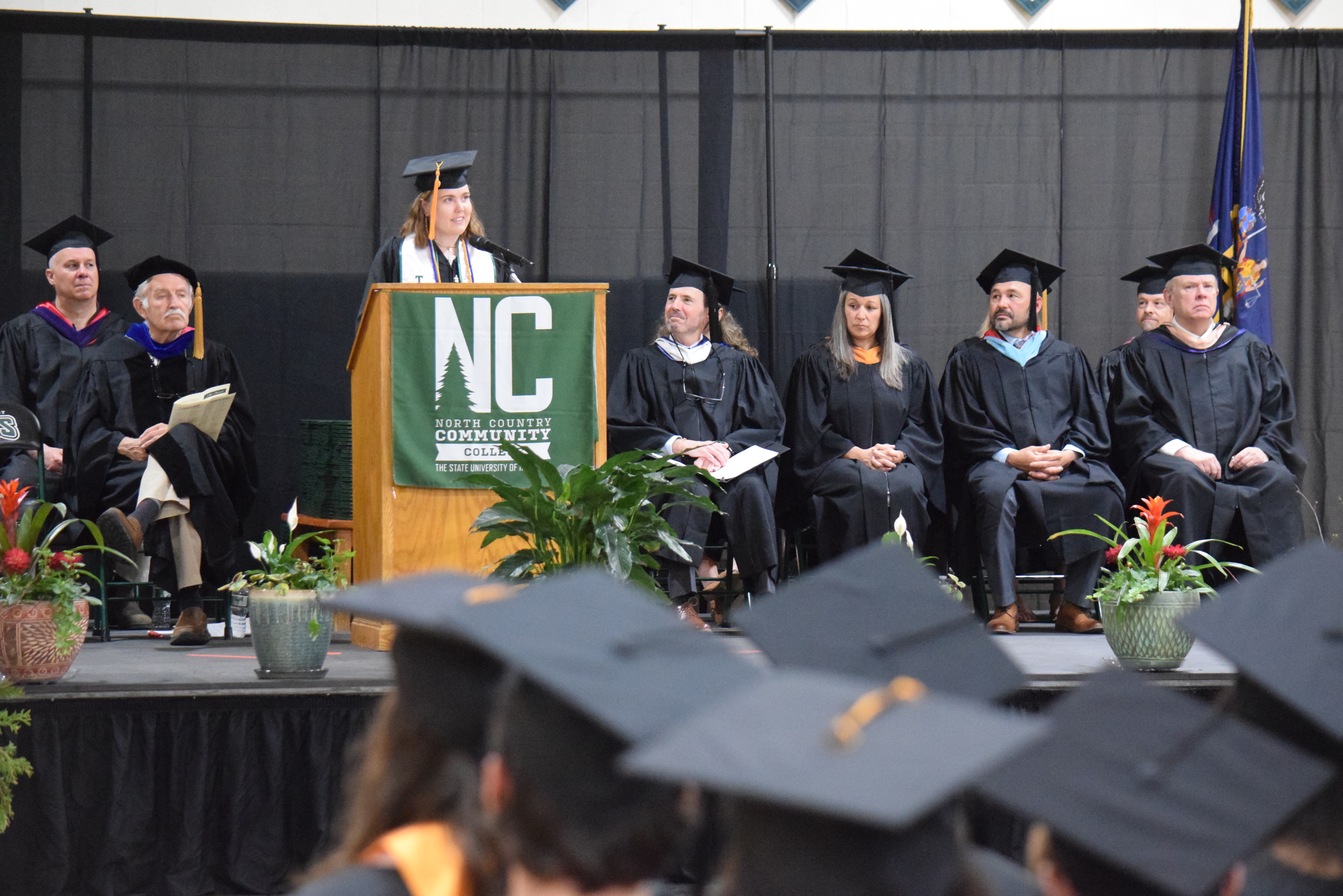 A speaker addresses a crowd of college graduates as they sit in the audience