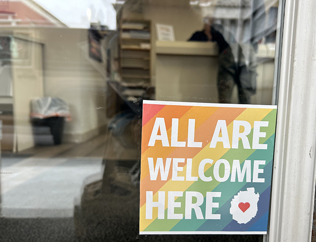 A sign posted on a business that says All Are Welcome Here