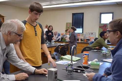 An instructor works with students in a science lab.