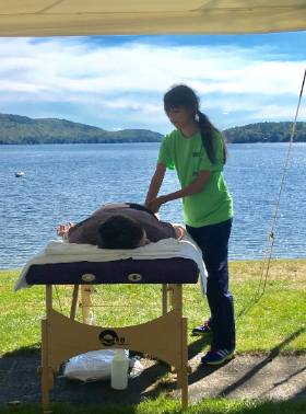 An NCCC student giving a massage to a person outside next to a lake
