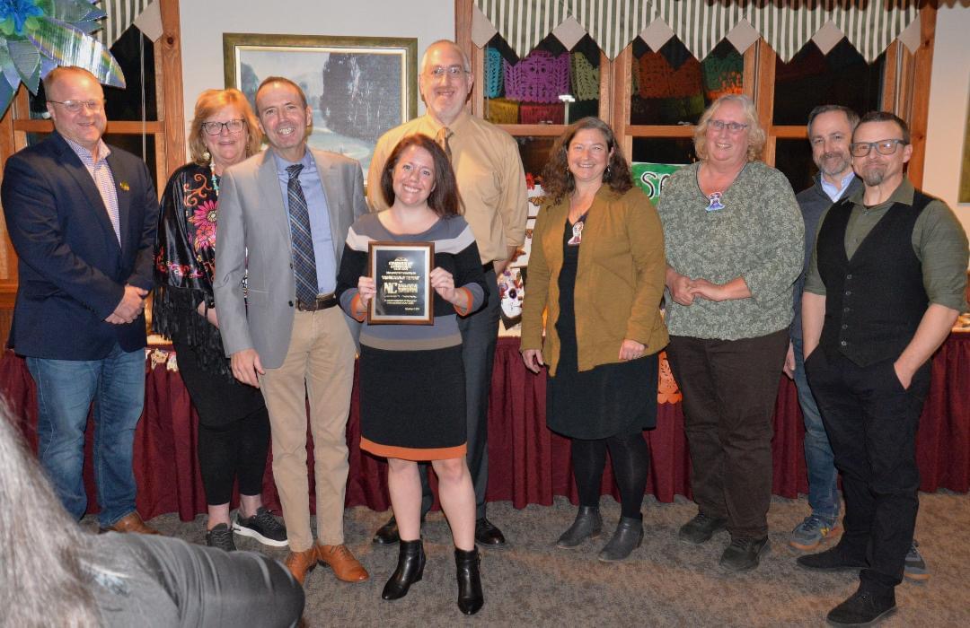 North Country staff and faculty stand facing the camera with one person holding an award