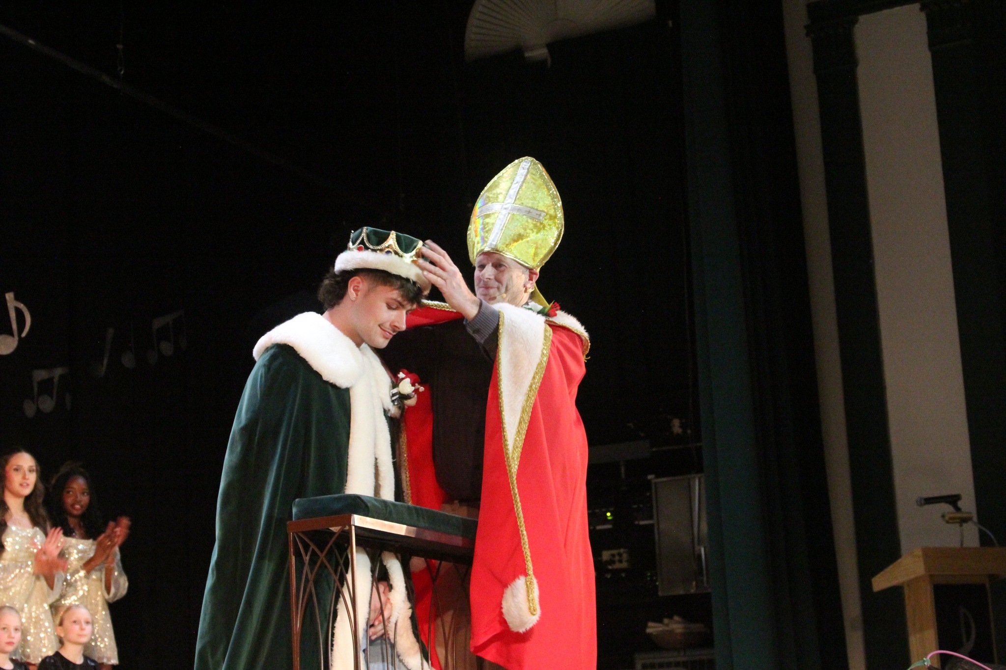 Owen McRae kneels as a crown is placed on his head on stage during Winter Carnival coronation.