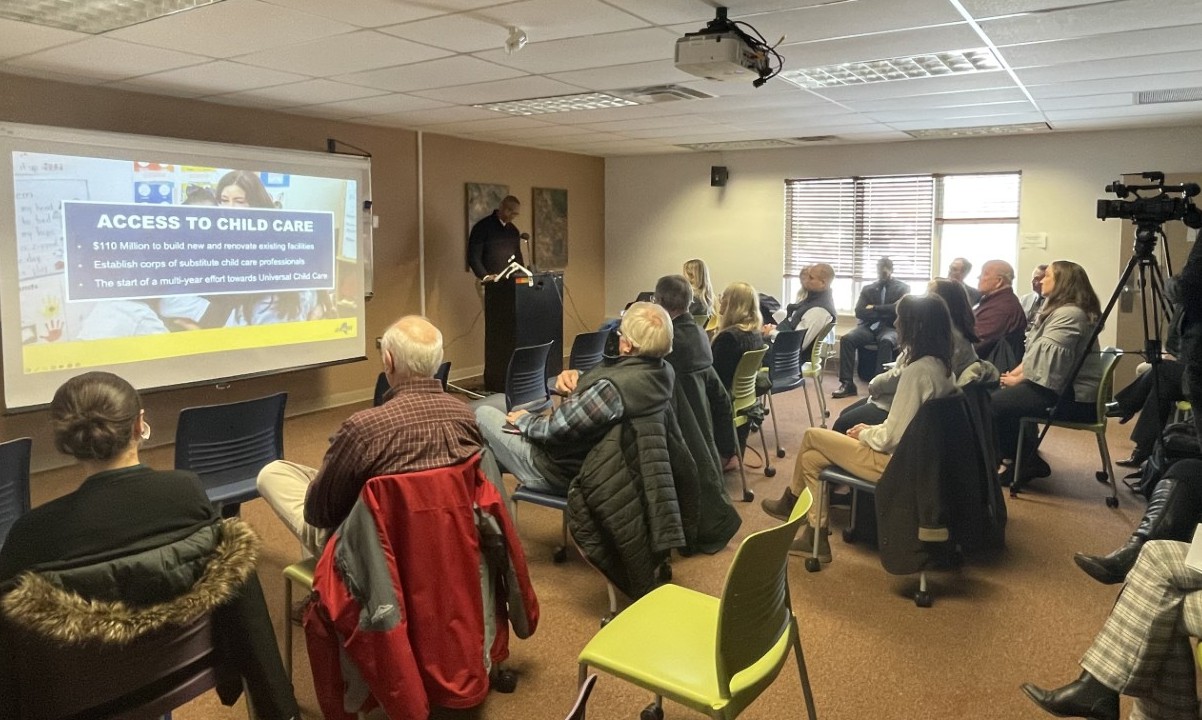 People sit in a classroom and listen to a person speak at a podium