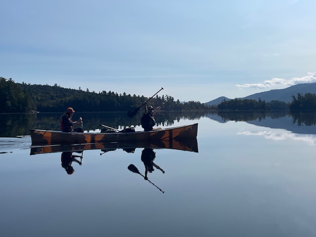 Students paddle in a canoe across Middle Saranac